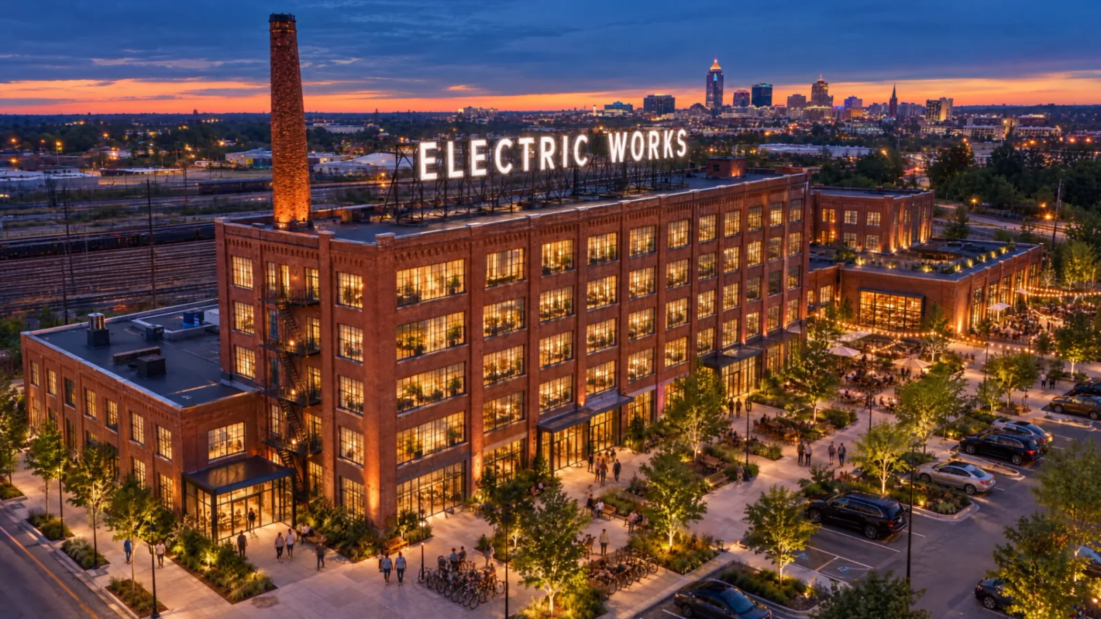 Illustration of the restored Electric Works campus in Fort Wayne at dusk, windows lit and the rooftop sign glowing.